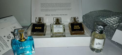 Customer's OUD Supreme BUNDLE displayed in an open box with three assorted fragrance bottles on a table.