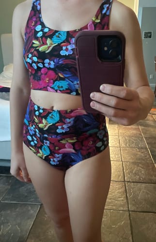 Reviewer wearing a colorful two-piece swimsuit with a floral pattern and high-waisted bottoms.