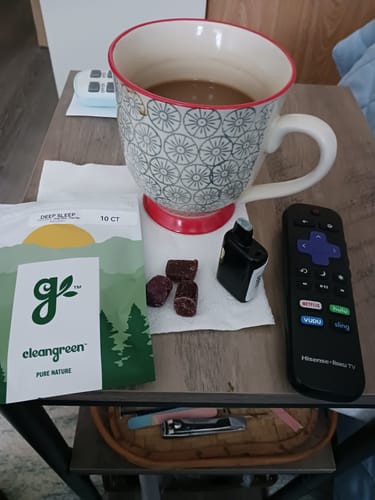 Customer's DeepSleep Gummies pouch with three gummies on a napkin on a bedside table next to a mug.