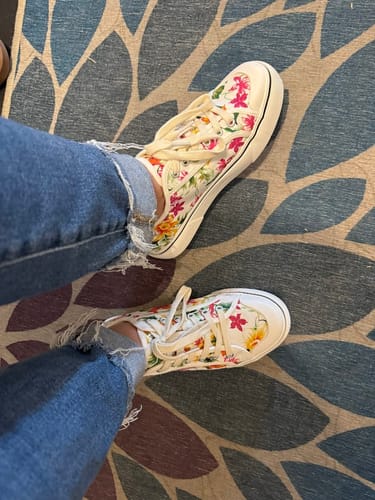 A customer's on-foot view of the white floral Corky's sneakers paired with cuffed jeans.