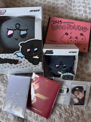 Reviewer's K-POP RANDOM BOX showing ATEEZ merchandise, including two plush toys, albums, and a photocard.