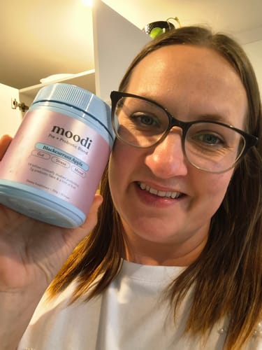 Reviewer smiling while holding a tub of Blackcurrant Apple Pre + Probiotic Blend.
