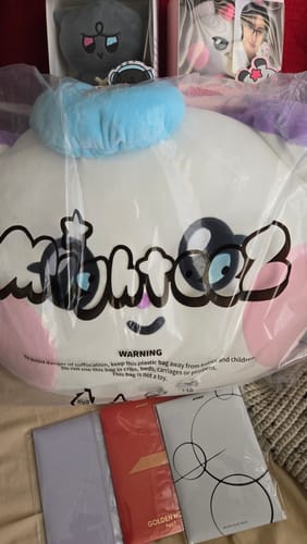 Customer shows items from their K-POP RANDOM BOX, including a large character pillow, albums, and two plush keychains.