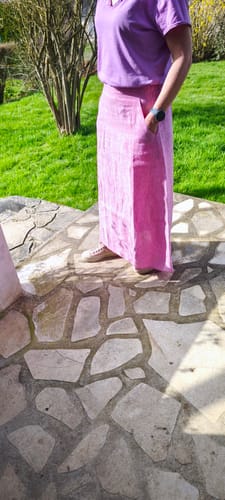 Cliente portant la jupe longue Maya en lin rose pep's à l'extérieur, avec une main dans la poche.