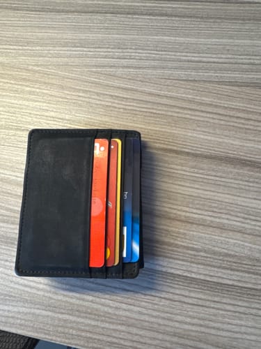 Reviewer's black Flap Boy wallet filled with multiple cards, sitting on a wooden table.