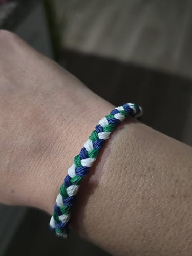 Close-up of a customer's wrist wearing the woven DAVID Bracelet in blue, green, and white.