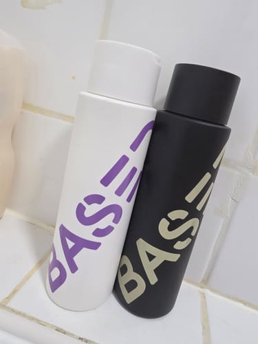 Customer's Shower Duo, a black bottle and a white bottle, resting on a white tiled surface.