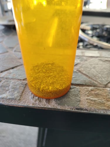 Close-up: A customer's Roll Ready Ground flower showing its fine consistency inside an orange container.