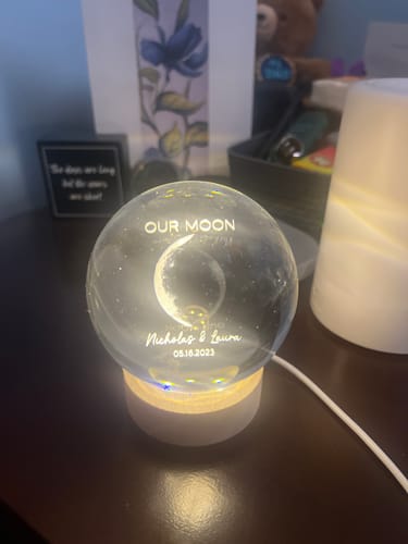 Reviewer's personalized crystal ball night light glowing on a dark table, illuminating the custom moon phase and text inside.