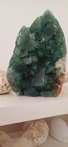 La Fluorine Forme libre d'une cliente, un grand cristal vert, posé sur une étagère.