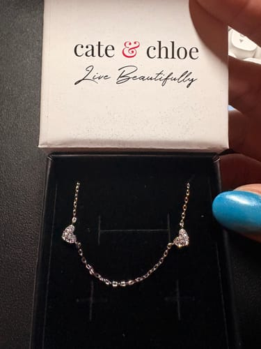Customer holding the Irene Heart Station Necklace with sparkly crystals in its Cate & Chloe gift box.
