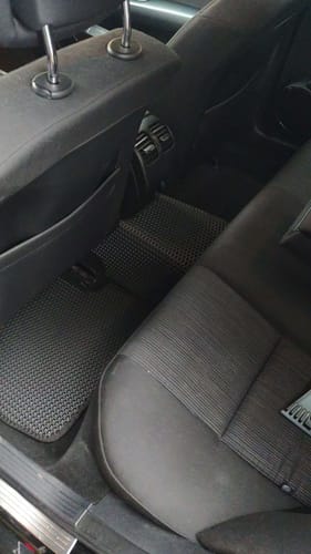 Recenzent pokazuje dopasowane, czarne dywaniki samochodowe zainstalowane na podłodze tylnych siedzeń.