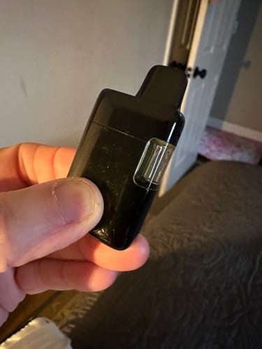 Close-up of a customer holding their empty black Calm Vape.