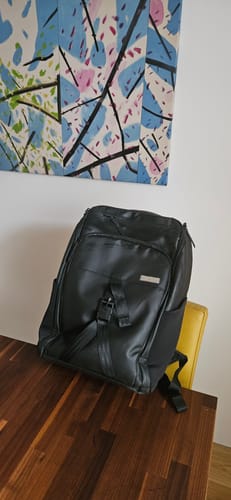Customer's black backpack resting on a chair at a wooden table.
