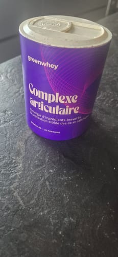 Le pot violet du produit Complexe Articulaire d'un client, posé sur une table foncée.
