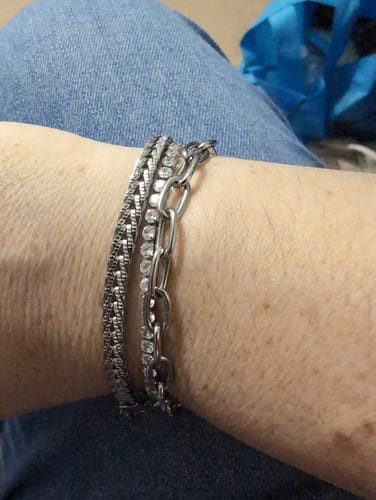 Customer's close-up of three layered silver-toned bracelets on their wrist.