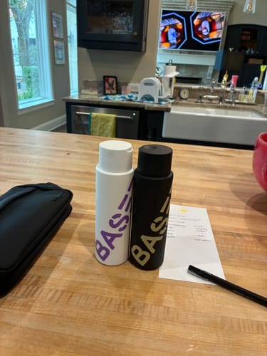Customer's Shower Duo, with one white bottle and one black bottle, sitting on a wooden kitchen island.