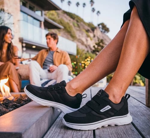 Customer wearing black CareStep shoes with white soles and velcro straps, relaxing on a wooden deck.