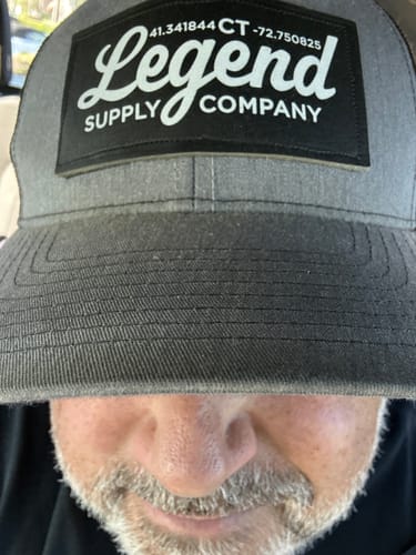 Close-up of a customer wearing a grey Legend Supply Company branded trucker hat.