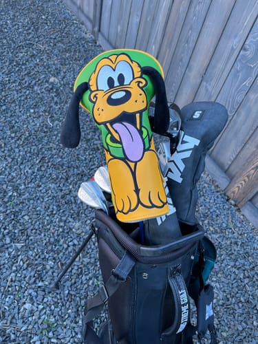 Customer's Disney Pluto driver headcover on a club in a black golf bag outdoors.