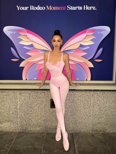 Customer wearing the light pink Naked Rose Tank Bodysuit in front of a butterfly mural.