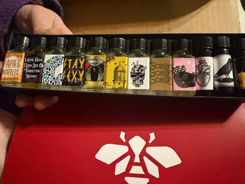 Customer holding the open Founder's Favorites Collection Box, showing a row of labeled perfume oils above the red box.