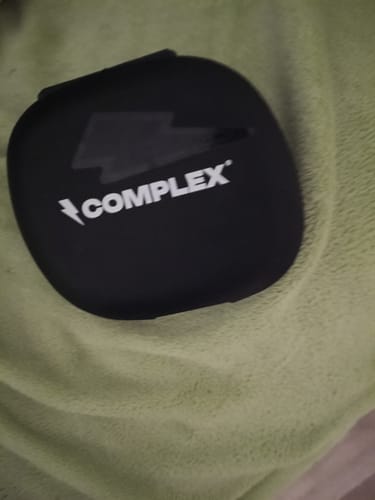 Customer's black Complex pill box with its lid closed, shown on a green towel.