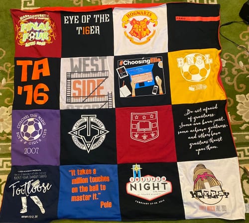 Reviewer's colorful T-Shirt Quilt spread out, showcasing a variety of custom t-shirt panels from their son's past.
