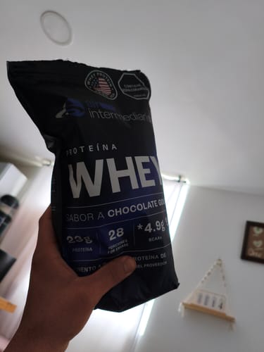 Cliente sosteniendo la bolsa negra de Proteína Whey sabor chocolate en su mano.