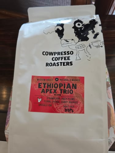 A customer's white bag of Ethiopian Apex Trio coffee, showing the red label with blend details.