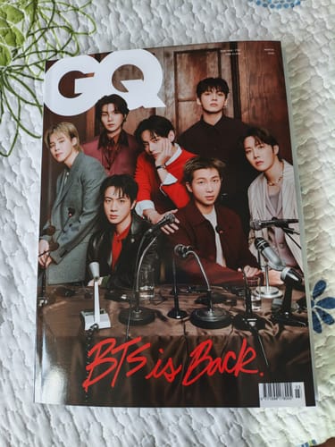 Customer's copy of the GQ KOREA MAGAZINE with the band BTS on its cover, laid flat on a bed.