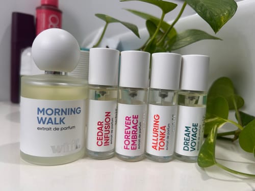 Reviewer's small sample bottle of Alluring Tonka perfume, shown alongside other scents from their collection.