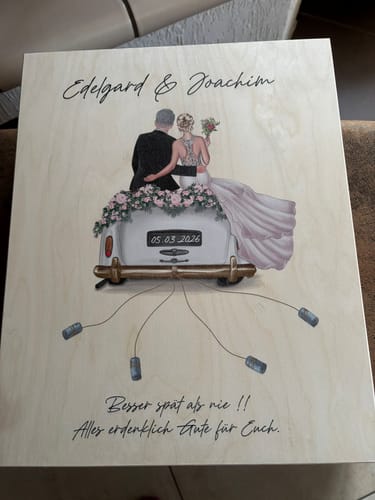 Rezensent zeigt eine personalisierte Holztafel mit Hochzeitsauto-Motiv, Namen und dem Datum '05.03.2026'.