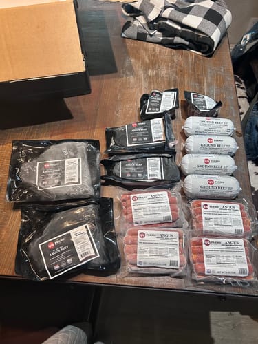 Customer's Beef & Steak Grilling Bundle, showing frozen steaks, ground beef, and franks laid out on a table.