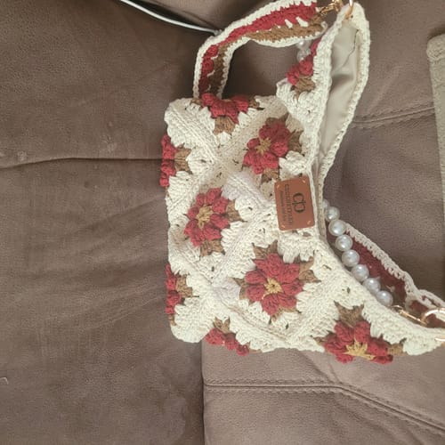 Customer's completed Garden Rose Hobo bag in cream and red, featuring a pearl handle, resting on a brown surface.