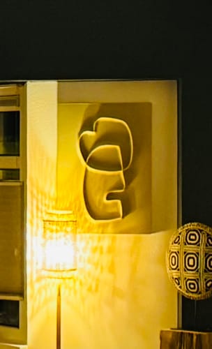 Recensent toont de Blythe wanddecoratie aan een muur, sfeervol verlicht door een warme lamp.