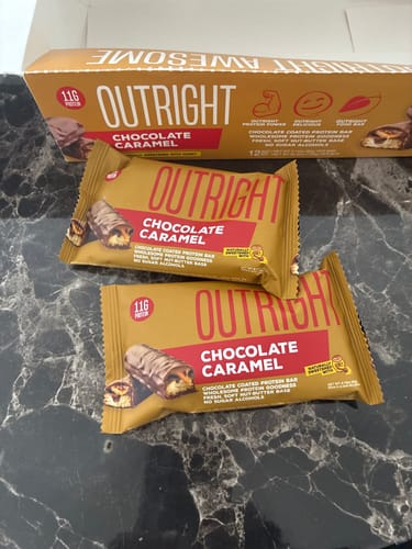 Reviewer's two Outright Chocolate Caramel protein bars on a countertop in front of the box.