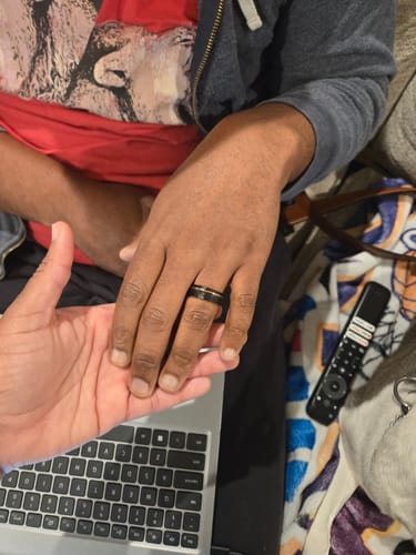 Customer's hand wearing the black Apollo ring with a rose gold inlay, held by another person.