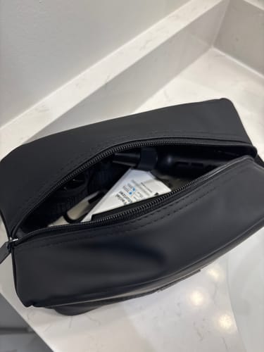 Customer's black Toiletry Bag, open on a counter and filled with various products.