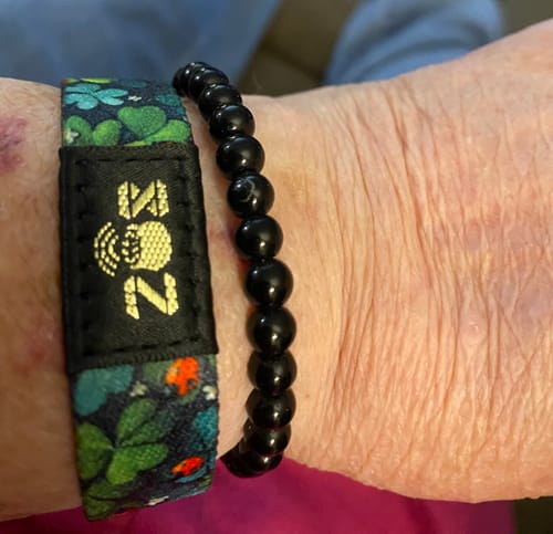Close-up of a reviewer's wrist showing the patterned Lucky You Bracelet next to a black beaded bracelet.