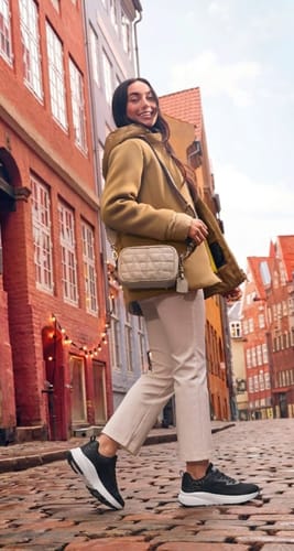 Reviewer walking on a cobblestone street in their black and white Wide Fit shoes.
