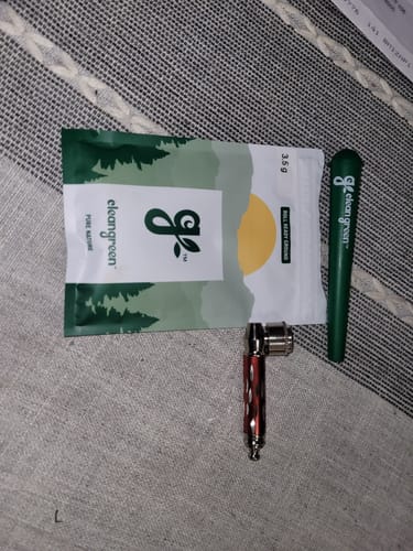 Customer's free green carry case displayed with a pouch of product and a small pipe.