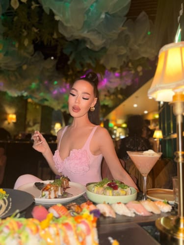 Customer seated at a restaurant table wearing the pink Naked Rose Tank Bodysuit.