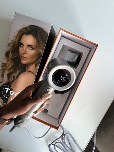 Recensent houdt de zilveren Ted Hilley Ionische Föhn vast, met het display dat 45°C aangeeft.