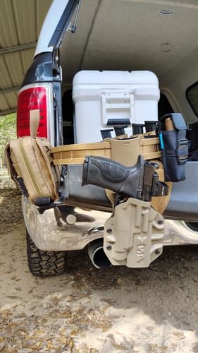 Customer's tan MSP OWB holster holding a handgun, shown on a tactical belt hanging from a vehicle.