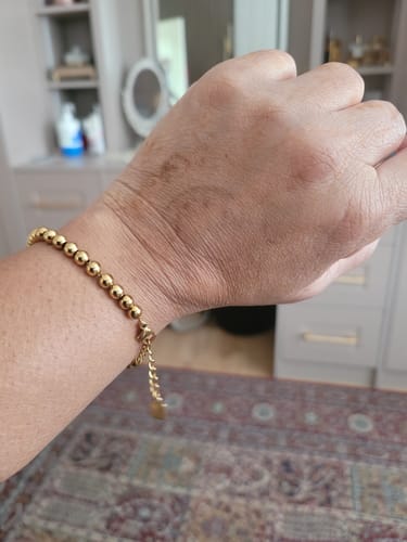 Customer's wrist featuring the bold, gold-beaded Tasbih Bracelet.