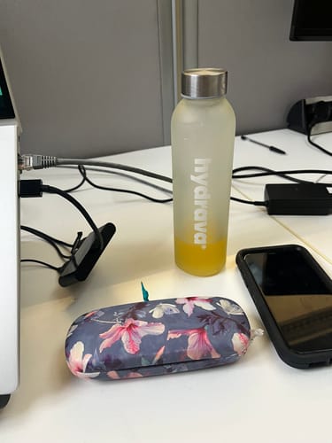 Customer's branded hydrava bottle with partially consumed yellow electrolyte drink on an office desk.