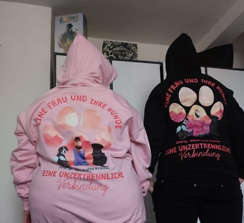 Rückansicht von zwei Rezensenten, die einen rosa und einen schwarzen personalisierten Hoodie mit individuellem Aufdruck tragen.