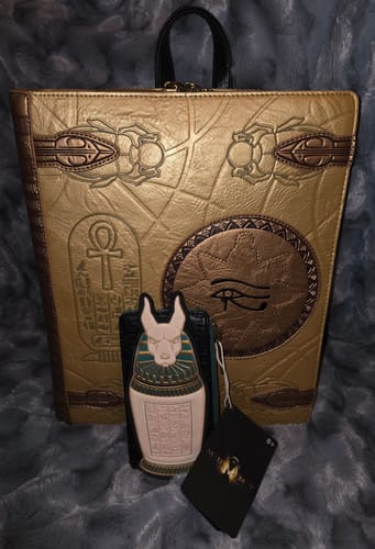 Reviewer's Loungefly The Mummy Card Holder with its urn design, shown with a matching golden 'Book of the Dead' backpack.