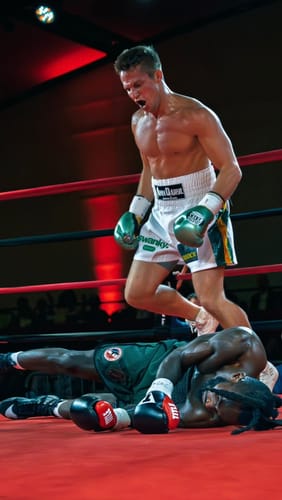 Reviewer, a professional boxer, celebrating a victory over an opponent in a boxing ring.